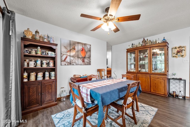 dining room with baseboards, a ceiling fan, a textured ceiling, and dark wood-style flooring
