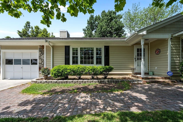 ranch-style house featuring a chimney, concrete driveway, and an attached garage
