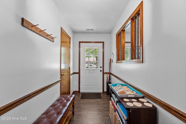 doorway with dark wood-type flooring, visible vents, and a textured ceiling
