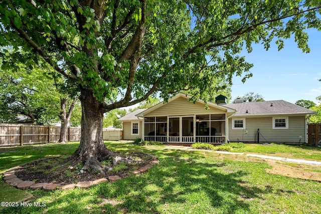 back of property featuring a lawn, a fenced backyard, and a sunroom