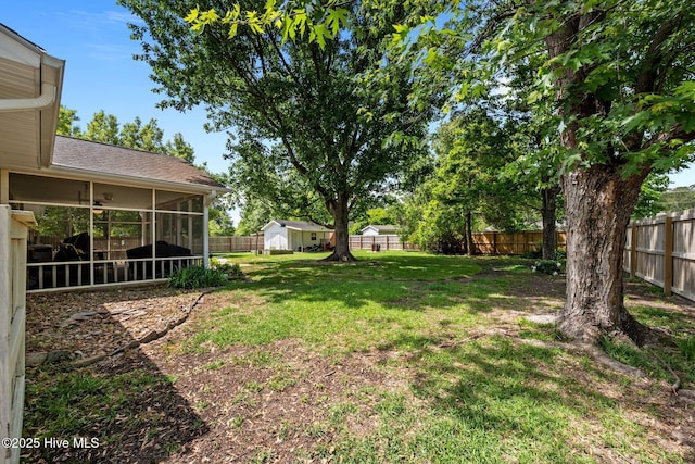 view of yard featuring a storage unit, a fenced backyard, a sunroom, and an outdoor structure