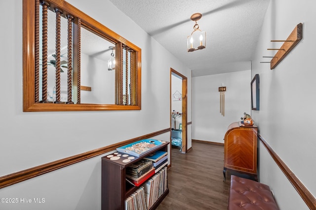 corridor featuring a textured ceiling, wood finished floors, and baseboards