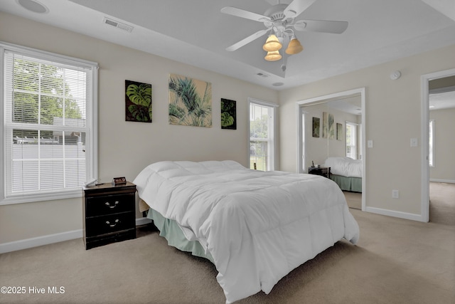 bedroom featuring baseboards, visible vents, light carpet, and ceiling fan