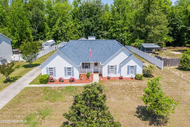 view of front of house with fence, covered porch, a shingled roof, and a front lawn