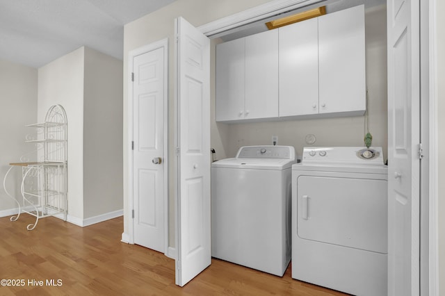 washroom featuring cabinet space, baseboards, light wood-type flooring, and washing machine and clothes dryer