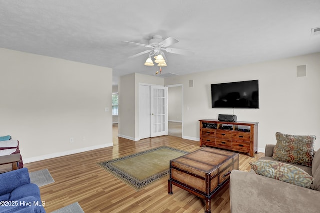 living area featuring baseboards, a ceiling fan, and wood finished floors