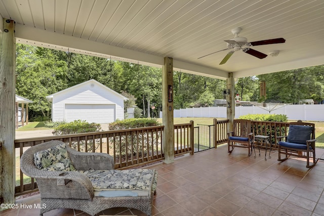 view of patio / terrace with a detached garage, fence, an outdoor structure, and ceiling fan