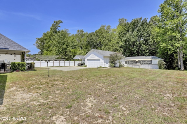 view of yard with fence, concrete driveway, and a garage
