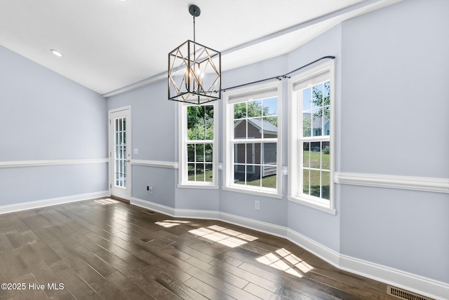 unfurnished dining area featuring plenty of natural light, dark wood finished floors, and a chandelier