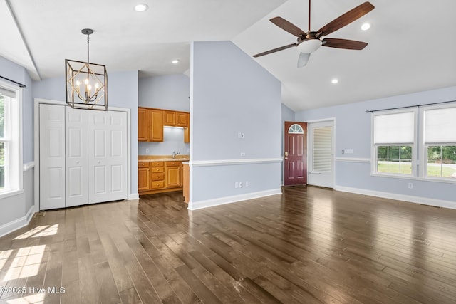unfurnished living room featuring a sink, ceiling fan with notable chandelier, dark wood finished floors, and lofted ceiling
