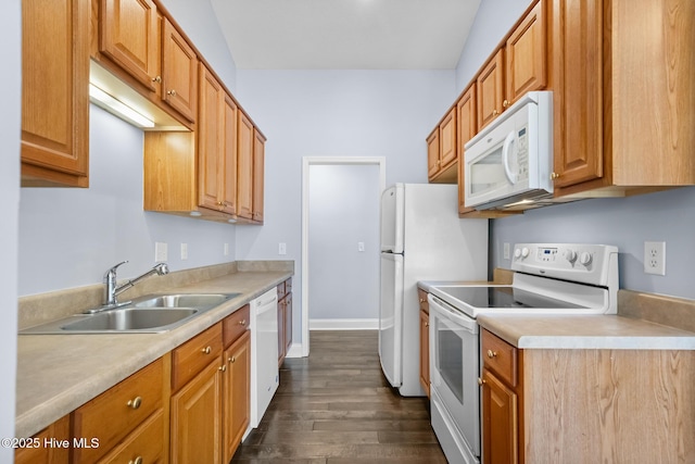 kitchen with a sink, light countertops, baseboards, dark wood-style floors, and white appliances