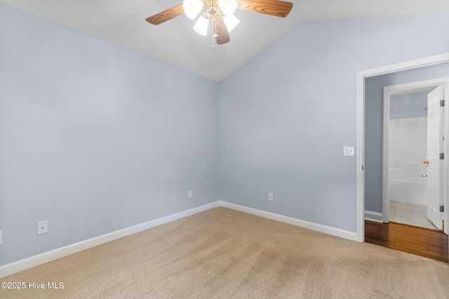 carpeted empty room featuring baseboards, ceiling fan, and vaulted ceiling