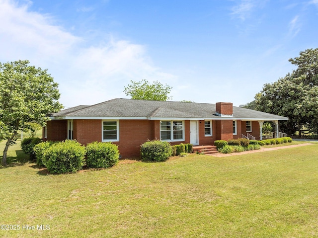 ranch-style home with a chimney, brick siding, and a front yard
