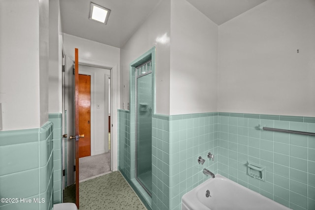 full bath with a shower stall, a bath, and a wainscoted wall