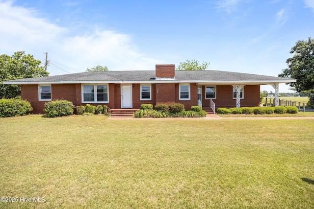 single story home featuring a chimney, brick siding, and a front yard