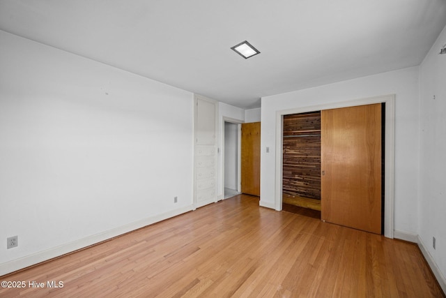 unfurnished bedroom with baseboards, light wood finished floors, and a closet