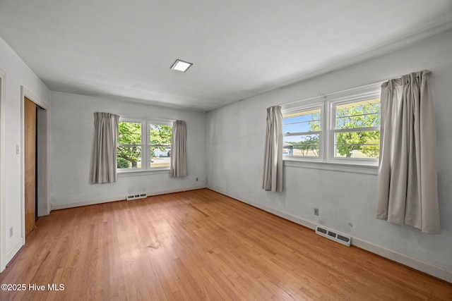unfurnished room with baseboards, light wood-style flooring, and visible vents