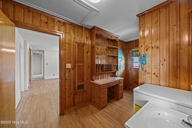 interior space featuring light wood-style floors, attic access, wooden walls, and laundry area