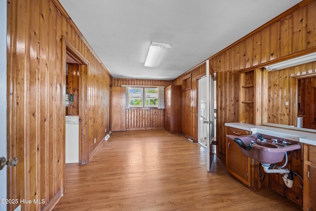 unfurnished room featuring light wood-style floors, baseboards, and wood walls