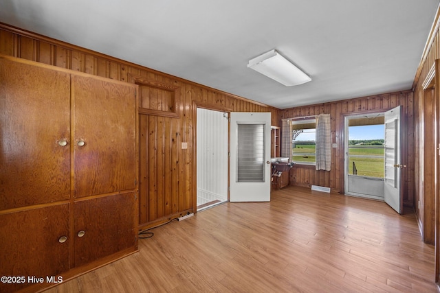 unfurnished bedroom featuring wooden walls and light wood-style floors