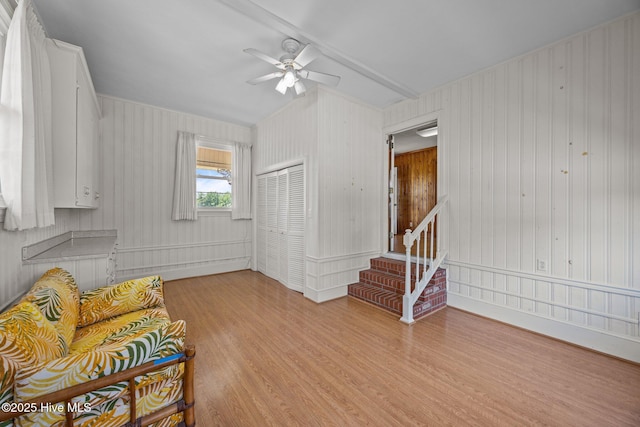 living area featuring light wood-style flooring, ceiling fan, and stairway