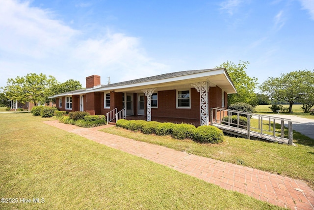 single story home with a porch, a chimney, a front yard, and brick siding