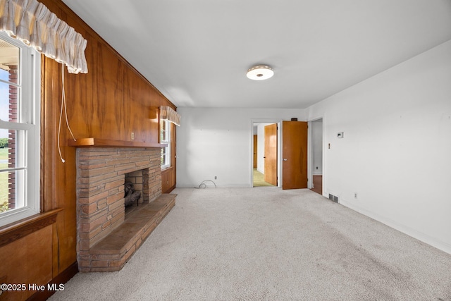 unfurnished living room featuring carpet floors, baseboards, a fireplace, and visible vents