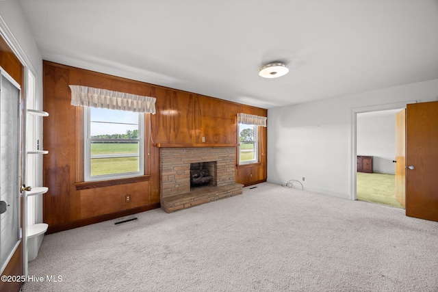 unfurnished living room with carpet floors, wood walls, and visible vents