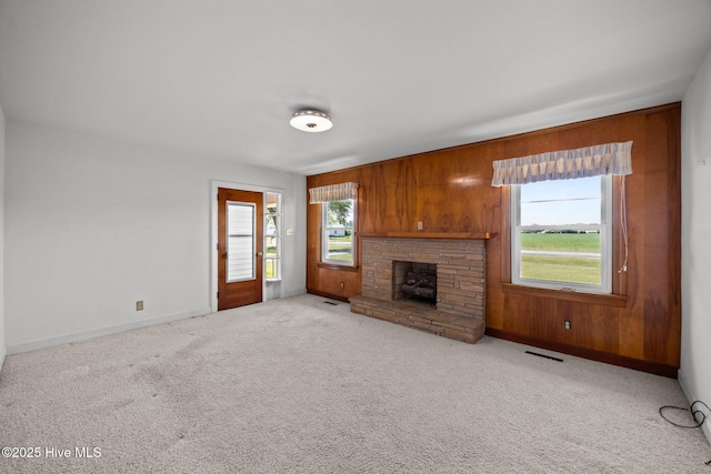 unfurnished living room featuring visible vents, wooden walls, and a healthy amount of sunlight