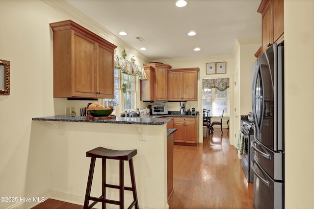 7102 Saybrook Dr, Wilmington, NC 28405 - kitchen with stainless steel appliances, a peninsula, a kitchen breakfast bar, crown molding, and light wood-type flooring