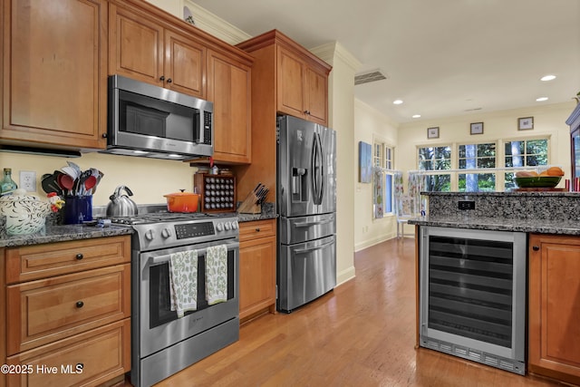 7102 Saybrook Dr, Wilmington, NC 28405 - kitchen featuring stainless steel appliances, beverage cooler, light wood finished floors, crown molding, and brown cabinetry