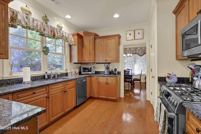 7102 Saybrook Dr, Wilmington, NC 28405 - kitchen featuring appliances with stainless steel finishes, ornamental molding, light wood-type flooring, a sink, and dark stone countertops