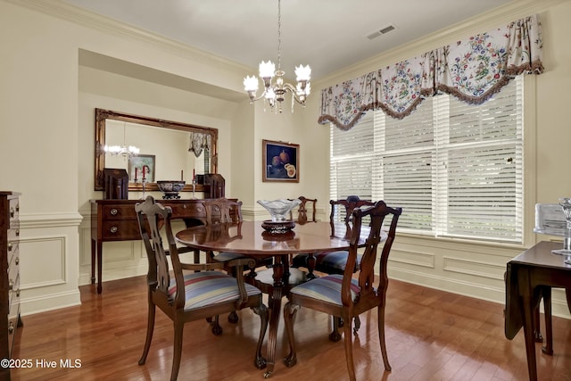 7102 Saybrook Dr, Wilmington, NC 28405 - dining space featuring a chandelier, a decorative wall, wood finished floors, plenty of natural light, and ornamental molding