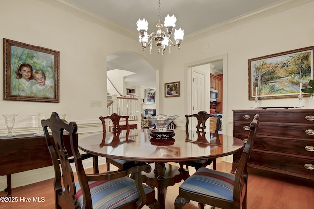7102 Saybrook Dr, Wilmington, NC 28405 - dining area featuring arched walkways, stairway, ornamental molding, wood finished floors, and a chandelier