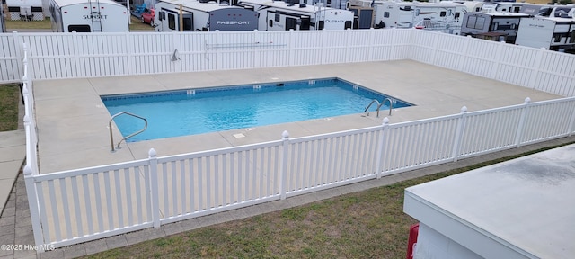 pool with a patio area, fence, and a residential view