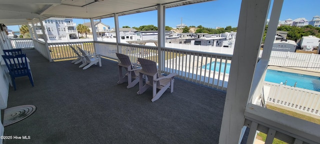 view of patio / terrace with a community pool, fence, and a residential view
