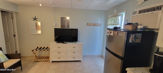 interior space featuring freestanding refrigerator, baseboards, a paneled ceiling, white cabinetry, and light tile patterned floors
