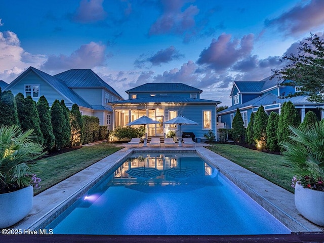 6221 Chalfont Cir, Wilmington, NC 28405 - back of house at dusk with an outdoor pool, a storage structure, a patio area, an outdoor structure, and a yard
