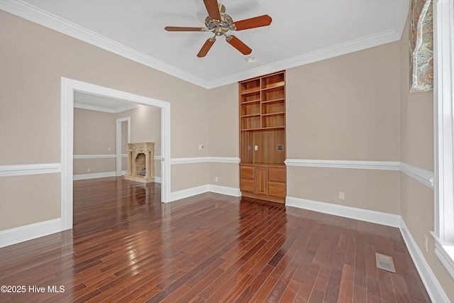 114 N Atlantic Ave, Southport, NC 28461 - spare room featuring dark wood-type flooring, a ceiling fan, baseboards, a fireplace with raised hearth, and crown molding
