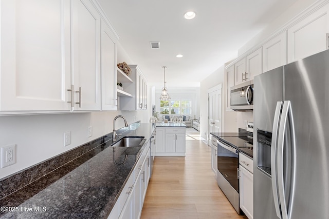 kitchen featuring a sink, open shelves, stainless steel appliances, and white cabinetry