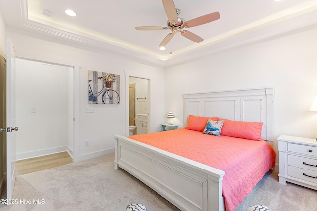 bedroom with light colored carpet, recessed lighting, a raised ceiling, and ensuite bathroom