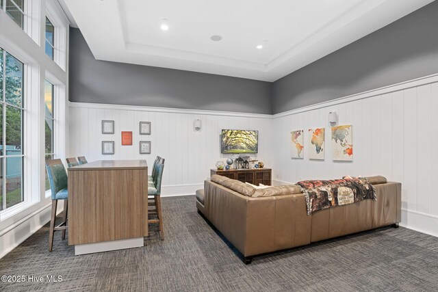 living room featuring recessed lighting, a tray ceiling, a wealth of natural light, and a wainscoted wall