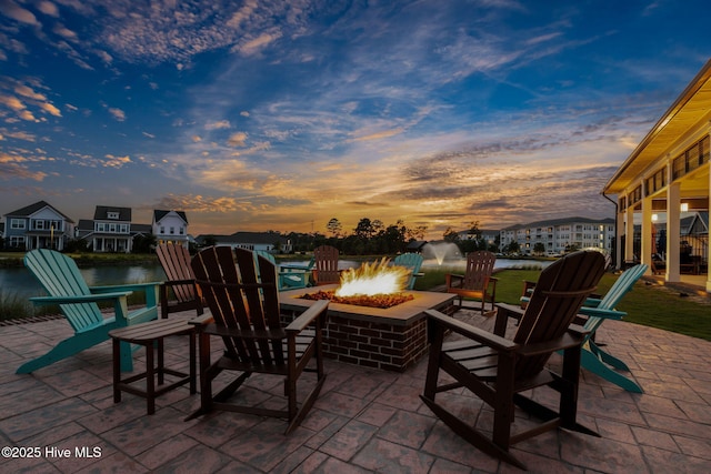 patio terrace at dusk featuring a water view and an outdoor fire pit