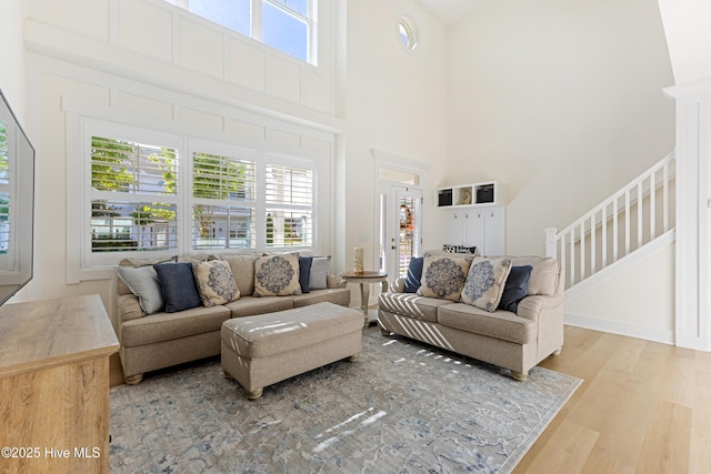 living room with stairs, a towering ceiling, and wood finished floors