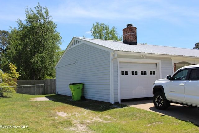 view of side of home with fence, a chimney, a yard, driveway, and metal roof