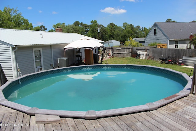 view of pool featuring a fenced backyard, a fenced in pool, central air condition unit, and a deck
