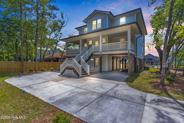 110 SW 26th St, Oak Island, NC 28465 - view of front of home with covered porch, driveway, a carport, fence, and stairs