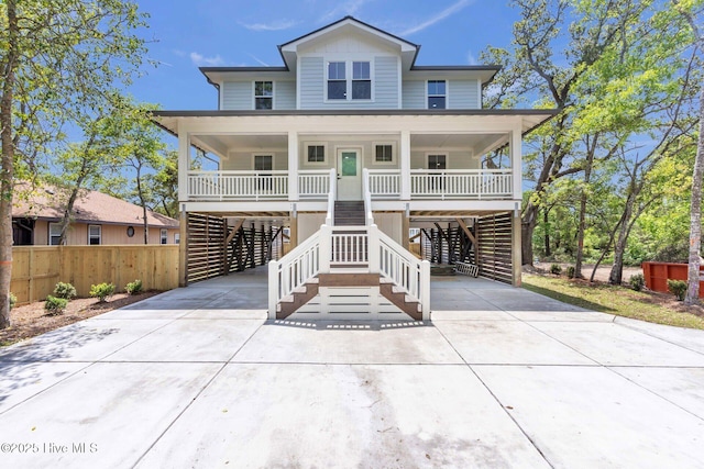 110 SW 26th St, Oak Island, NC 28465 - raised beach house featuring a porch, stairway, driveway, and a carport
