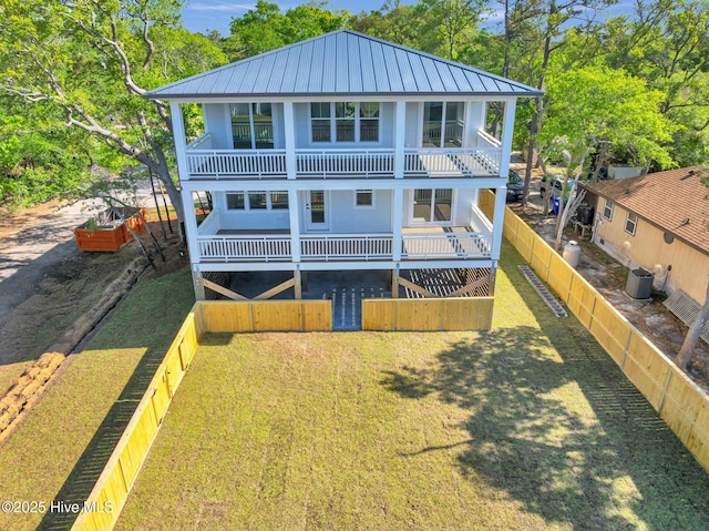 110 SW 26th St, Oak Island, NC 28465 - back of property with a standing seam roof, metal roof, central air condition unit, a balcony, and a fenced backyard