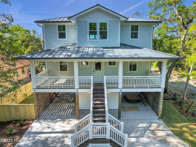 110 SW 26th St, Oak Island, NC 28465 - raised beach house with stairway, concrete driveway, a standing seam roof, covered porch, and metal roof